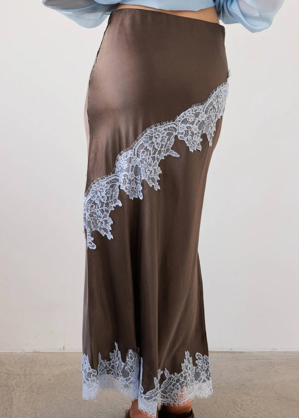Woman wearing a brown outfit with lace details in a neutral setting