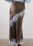 Woman wearing a brown outfit with lace details in a neutral setting