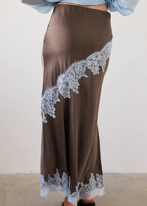 Woman wearing a brown outfit with lace details in a neutral setting