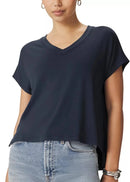 A woman wearing a dark navy blue short-sleeve V-neck t-shirt and light-wash blue jeans, shown from the nose down against a plain white background.