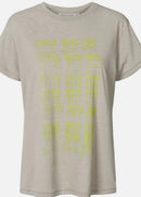 A light beige short-sleeve t-shirt with a yellow graphic print of stacked text on the front, displayed against a light grey background.