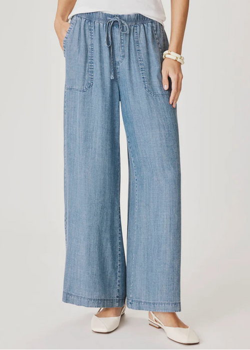 Woman wearing a light blue top and wide-leg pants on a white background