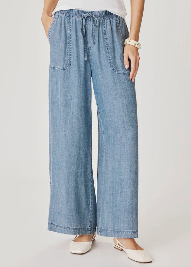 Woman wearing a light blue top and wide-leg pants on a white background