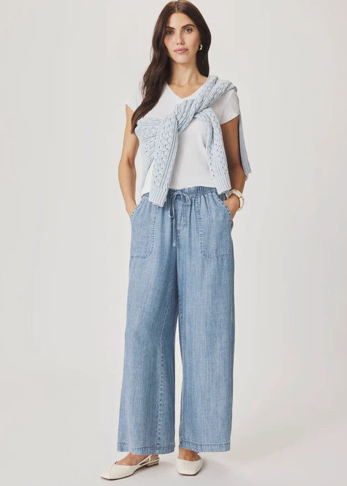 Woman wearing a light blue top and wide-leg pants on a white background