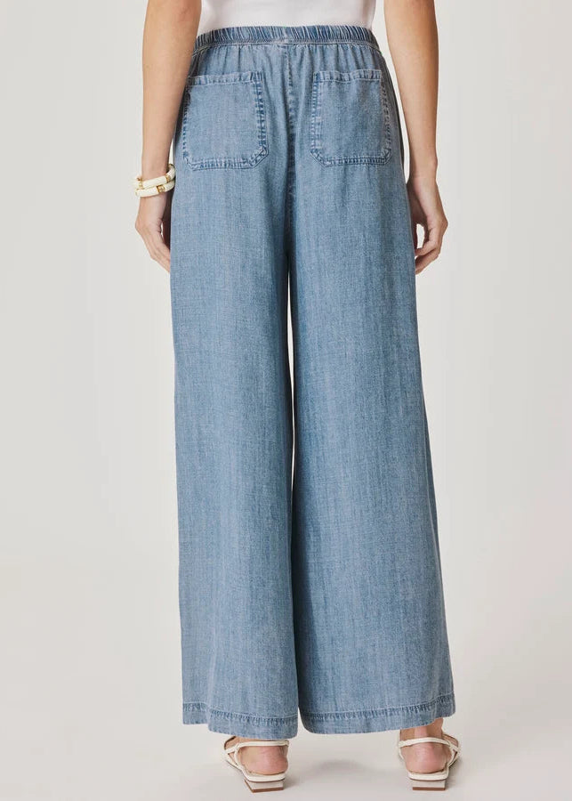 Woman wearing a light blue top and wide-leg pants on a white background