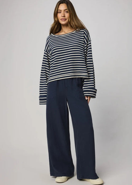 Woman wearing a striped sweater and wide-leg pants on a plain background
