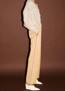 Woman wearing white top, beige pants,  on a brown background