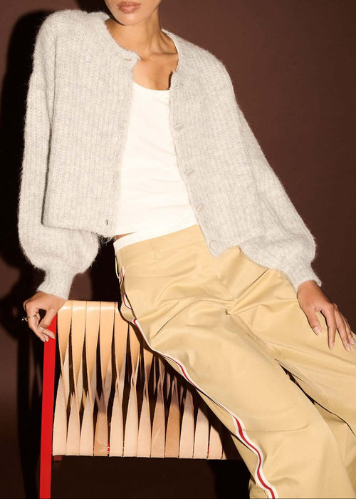 Woman wearing white top, beige pants,  on a brown background