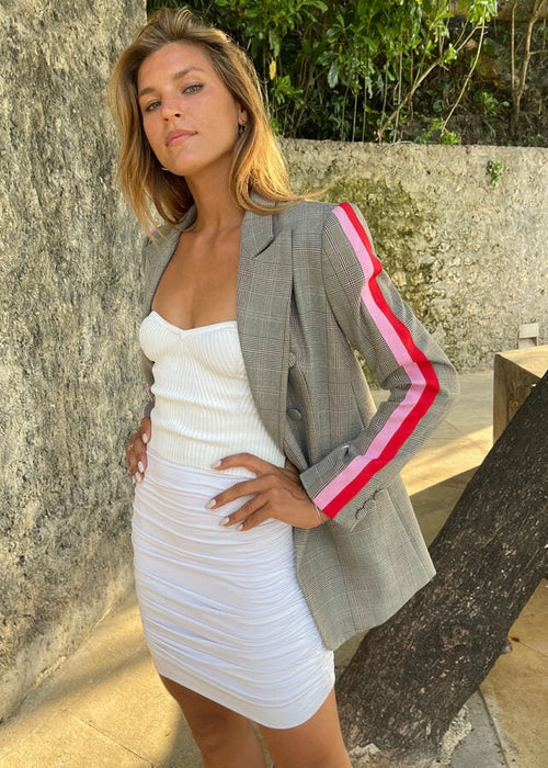 Woman wearing a grey blazer with pink accents against a textured wall.