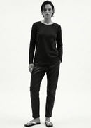 Person wearing a black long-sleeve top and pants on a white background