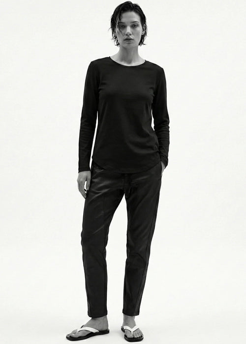 Person wearing a black long-sleeve top and pants on a white background