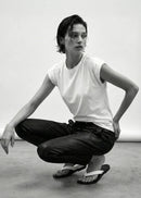 Person in a white t-shirt and black pants posing in a studio setting