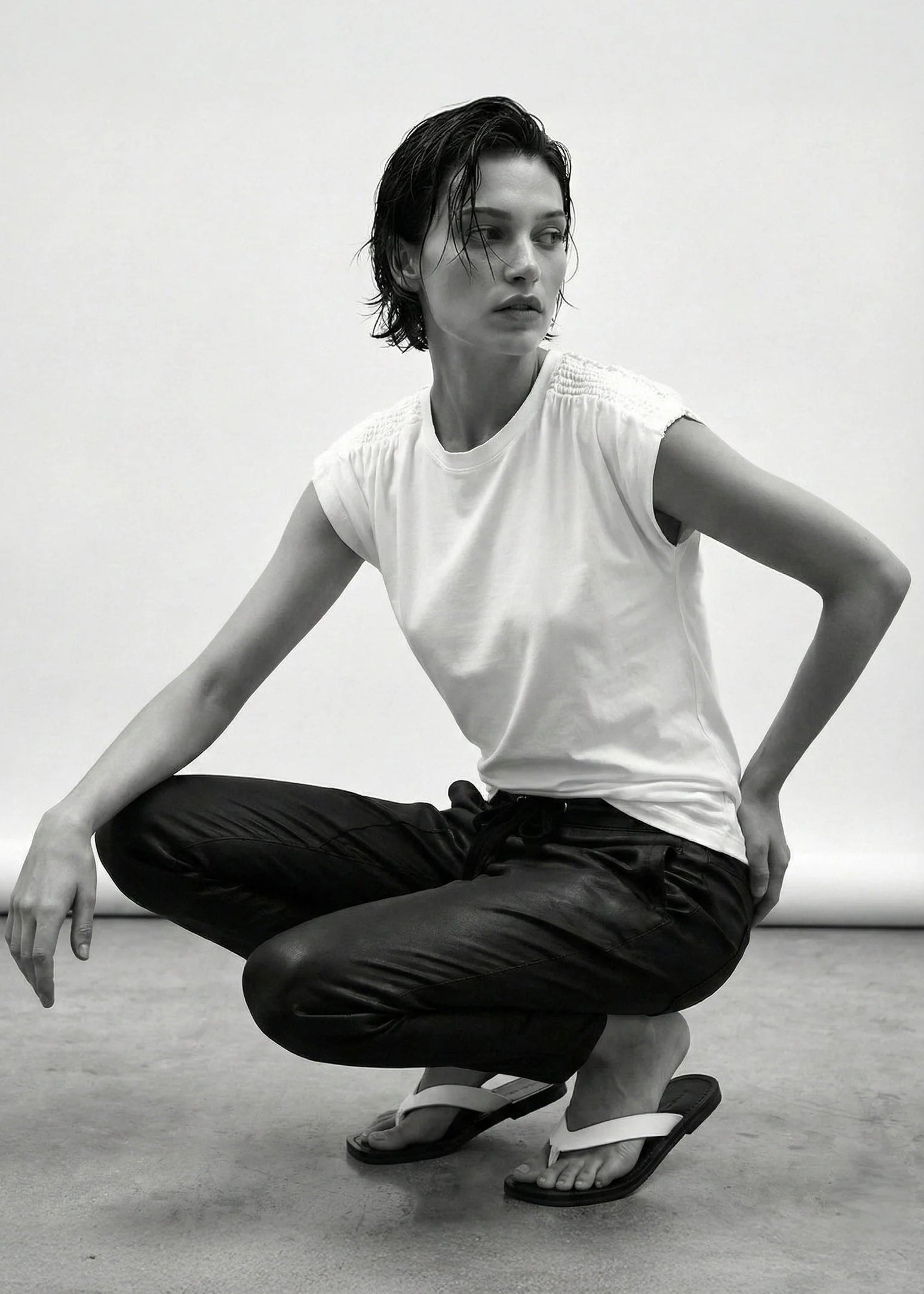 Person in a white t-shirt and black pants posing in a studio setting
