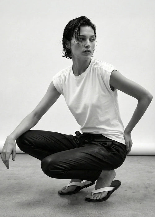 Person in a white t-shirt and black pants posing in a studio setting