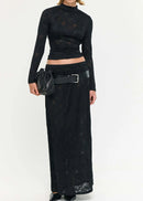 Woman wearing a black outfit with a long skirt and top on a white background