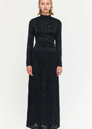Woman wearing a black outfit with a long skirt and top on a white background