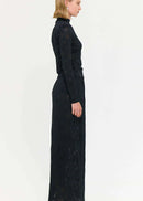 Woman wearing a black outfit with a long skirt and top on a white background