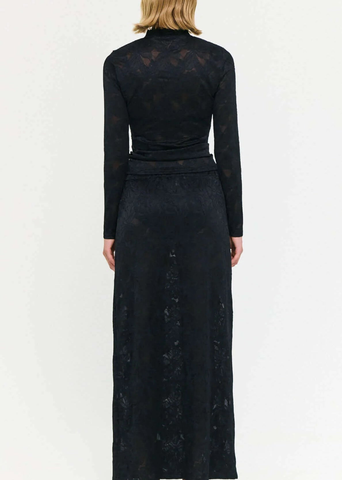 Woman wearing a black outfit with a long skirt and top on a white background