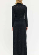 Woman wearing a black outfit with a long skirt and top on a white background