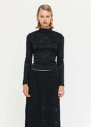Woman wearing a black lace top and long skirt on a white background