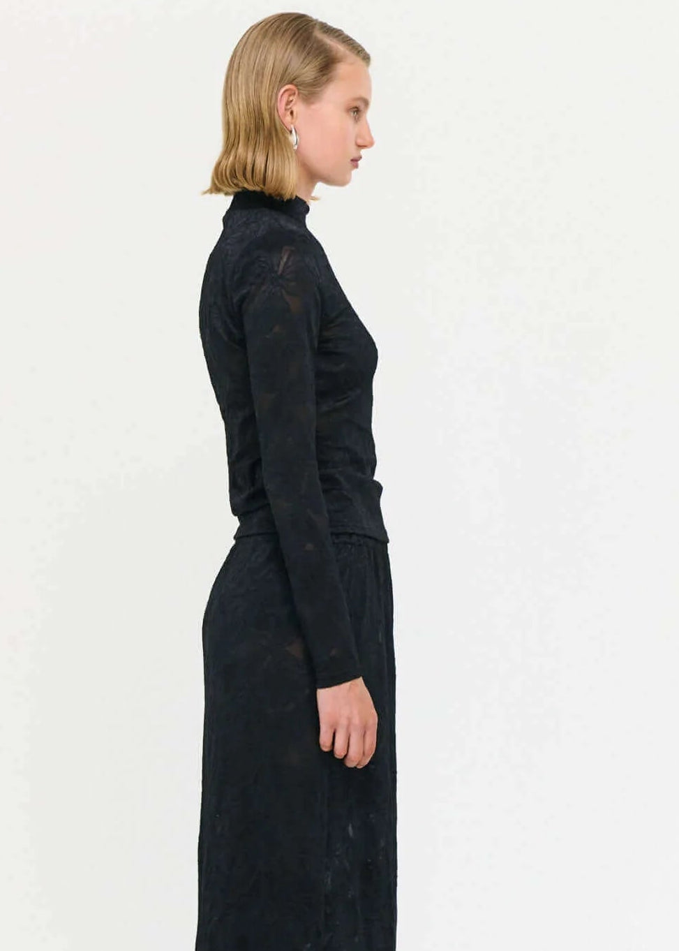 Woman wearing a black lace top and long skirt on a white background