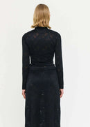 Woman wearing a black lace top and long skirt on a white background