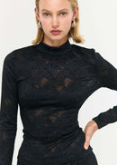 Woman wearing a black lace top and long skirt on a white background