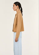 Woman wearing a tan jacket with black buttons on a white background