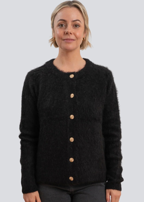 Woman wearing a black cardigan with button details on a light grey background