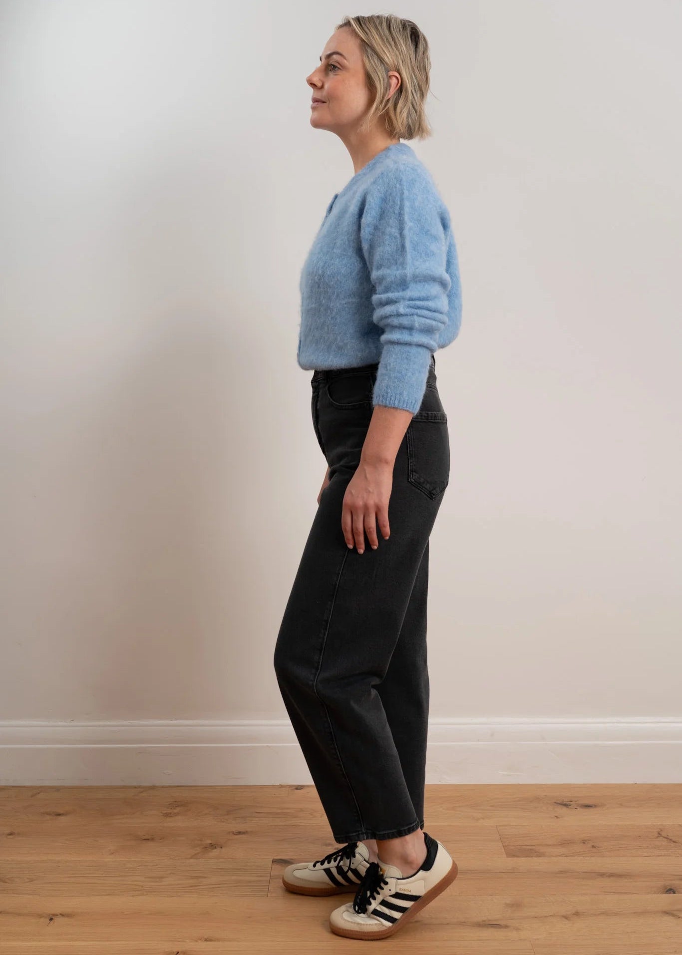 Woman wearing a light blue cardigan with buttons on a plain background