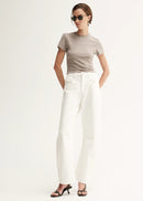 Woman wearing a beige t-shirt and white pants on a white background