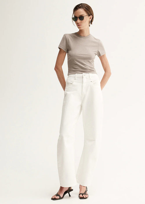 Woman wearing a beige t-shirt and white pants on a white background