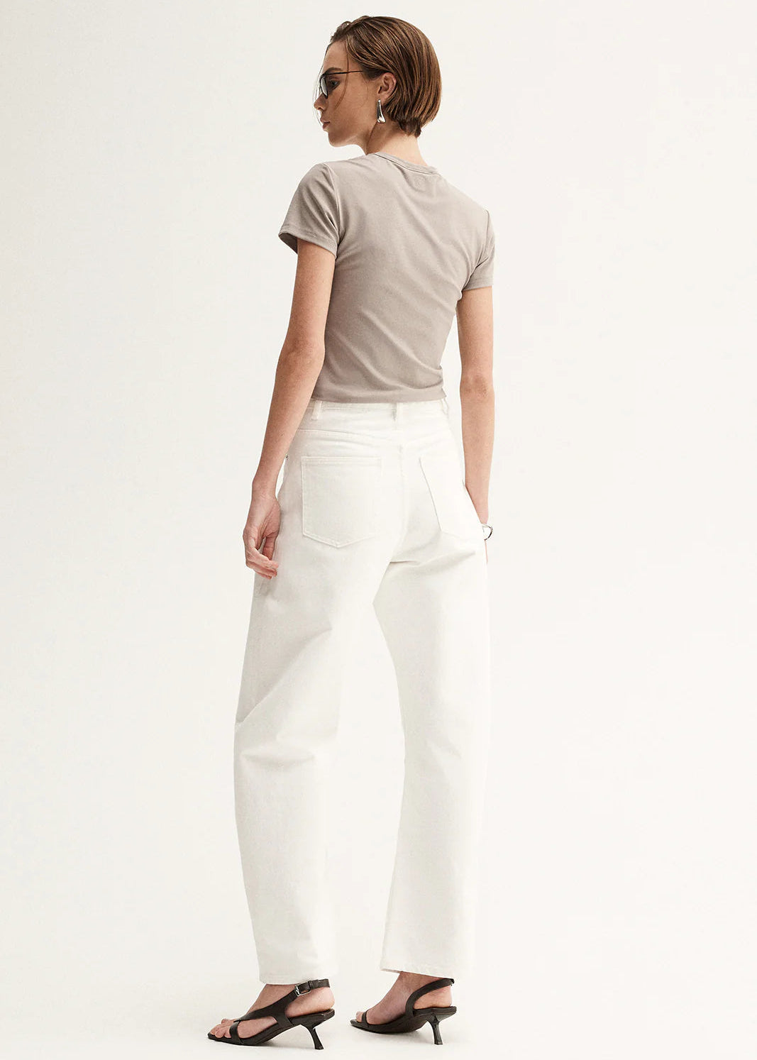 Woman wearing a beige t-shirt and white pants on a white background