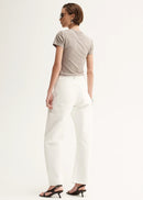 Woman wearing a beige t-shirt and white pants on a white background