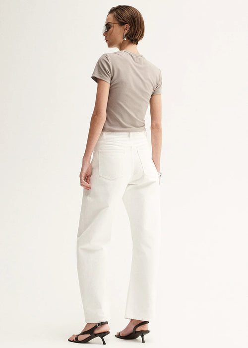 Woman wearing a beige t-shirt and white pants on a white background