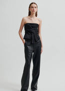 Woman wearing a black strapless top and black pants on a light grey background