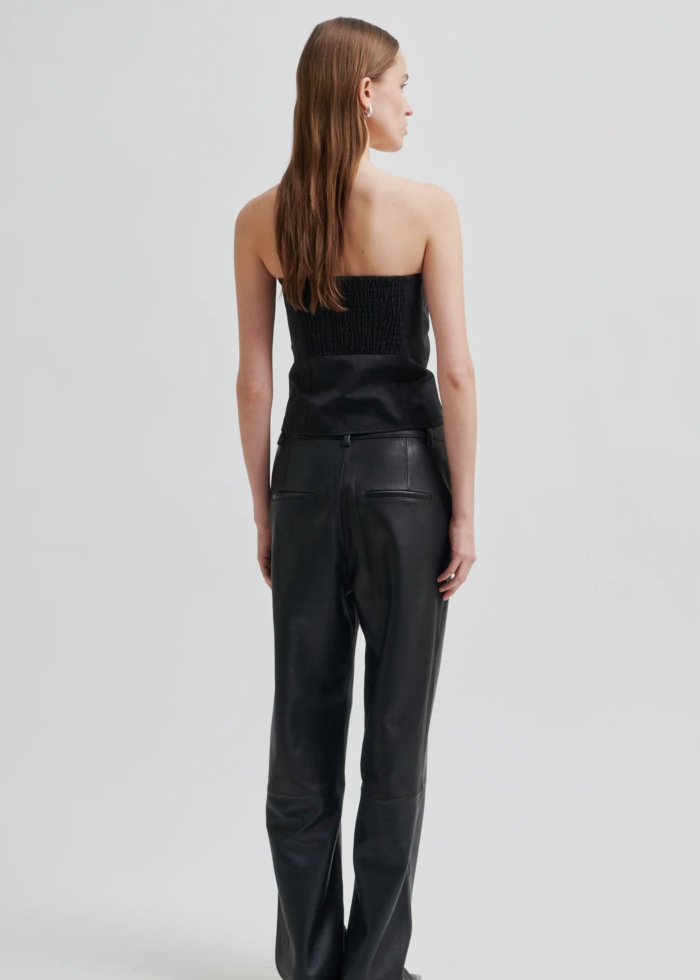 Woman wearing a black strapless top and black pants on a light grey background