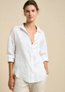 Woman wearing a white shirt and beige pants against a beige background