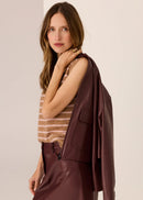 Woman wearing a brown and beige striped sleeveless top against a plain background