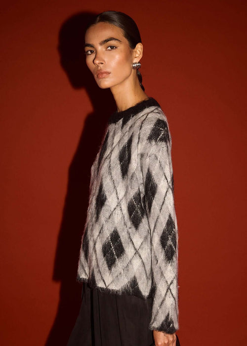 Woman wearing a black and white patterned sweater against a red background