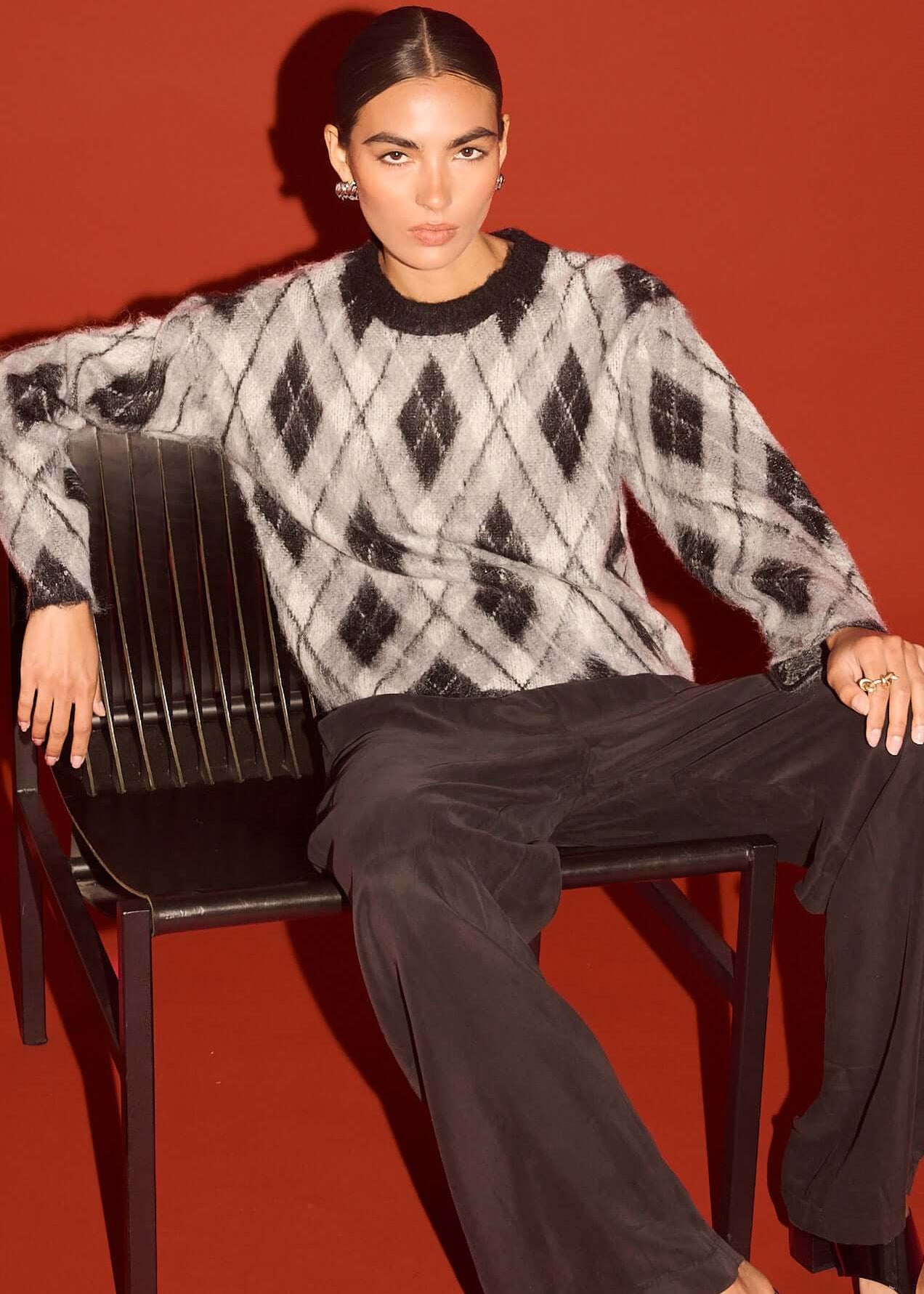 Woman wearing a black and white patterned sweater against a red background
