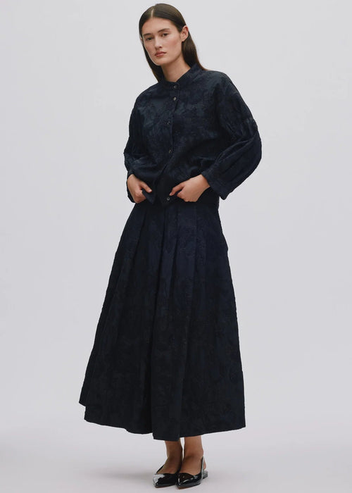 Woman wearing black textured blouse with button details on a white background
