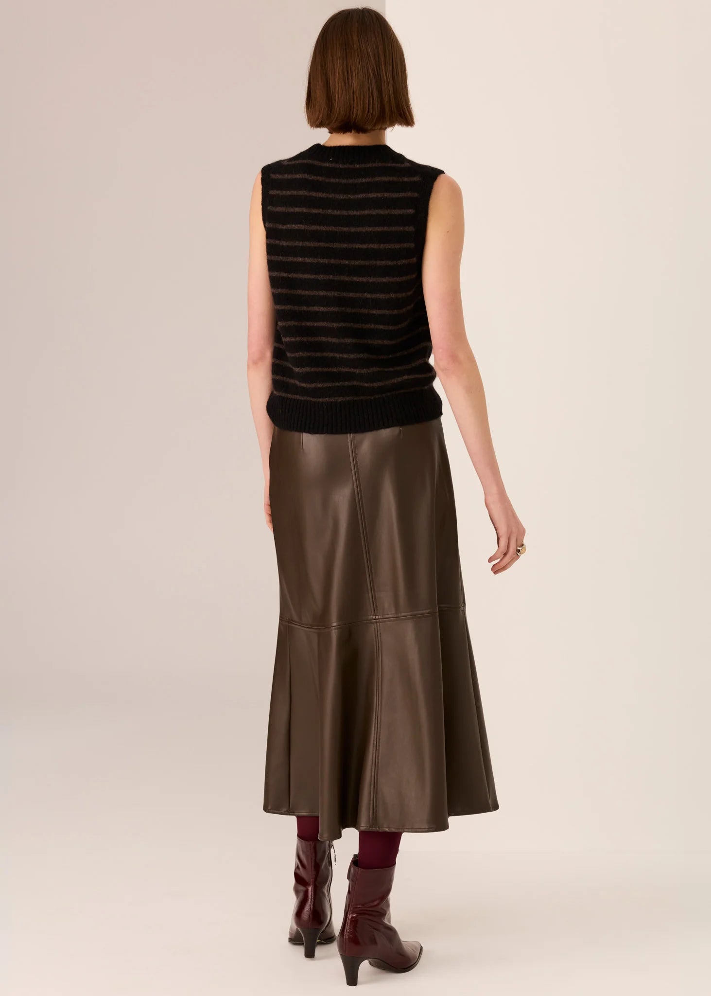 Woman wearing a black sleeveless top  on a beige background