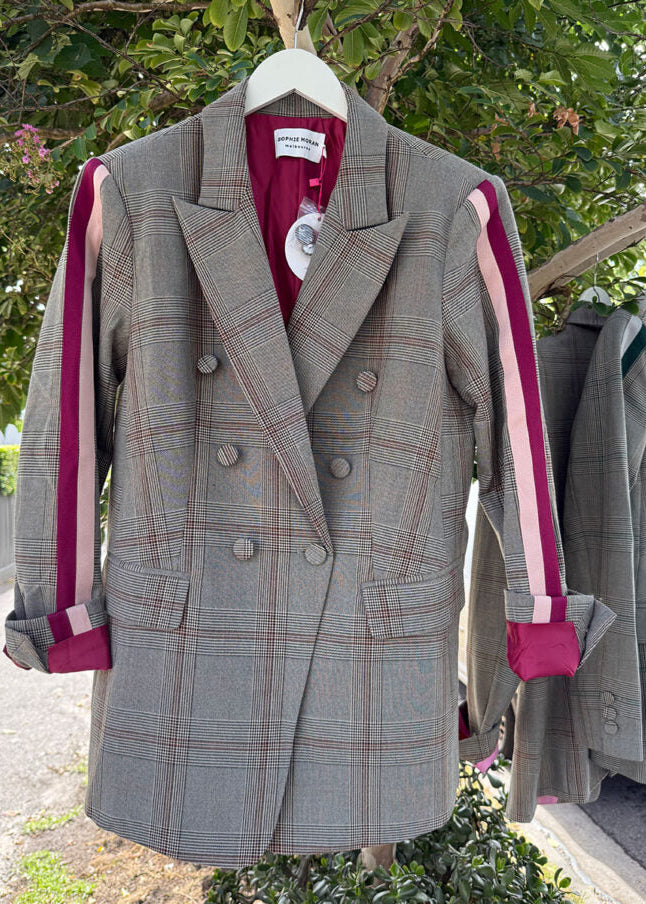 Gray plaid coat with pink accents hanging outdoors