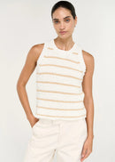 A woman modelling a sleeveless knit top with horizontal beige stripes on a white textured background, paired with white trousers, against a light grey studio backdrop.