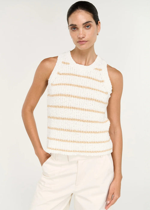 A woman modelling a sleeveless knit top with horizontal beige stripes on a white textured background, paired with white trousers, against a light grey studio backdrop.