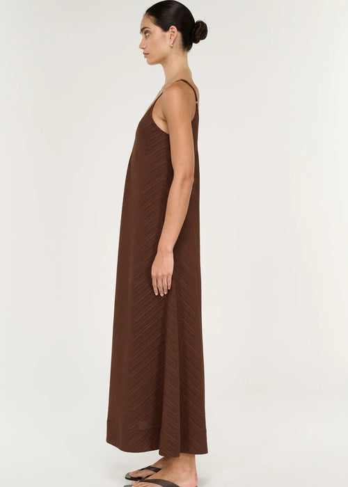 Woman modelling a sleeveless brown maxi dress on grey background