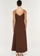 Woman modelling a sleeveless brown maxi dress on grey background viewed from behind