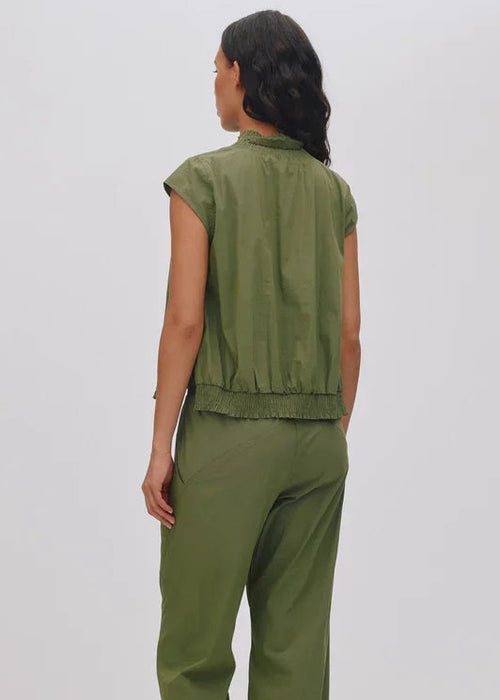 Woman wearing a green sleeveless top and pants on a white background