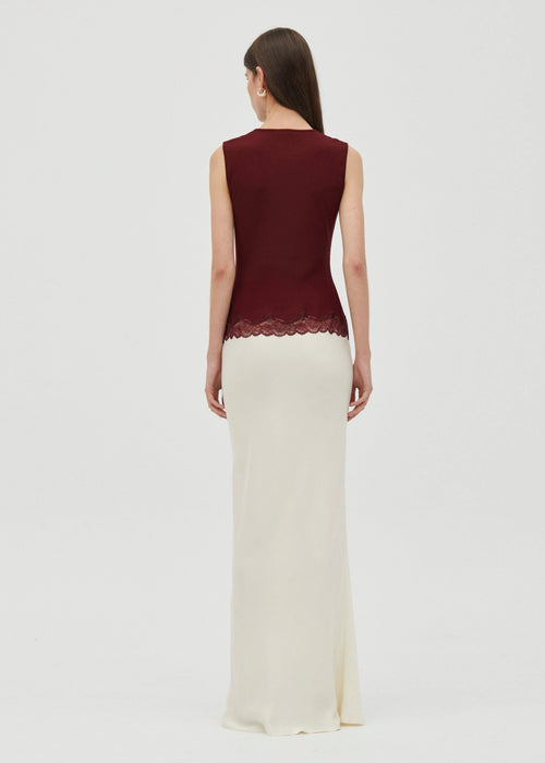 Woman wearing a crimson top and white bottom dress  on grey  background